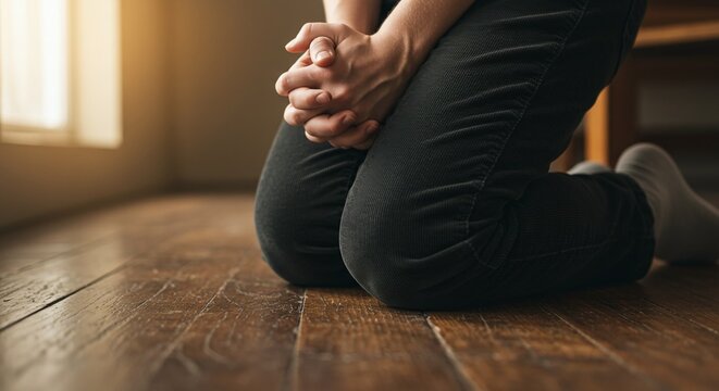 Close of a person kneeling in prayer, symbolizing faith and trust in God