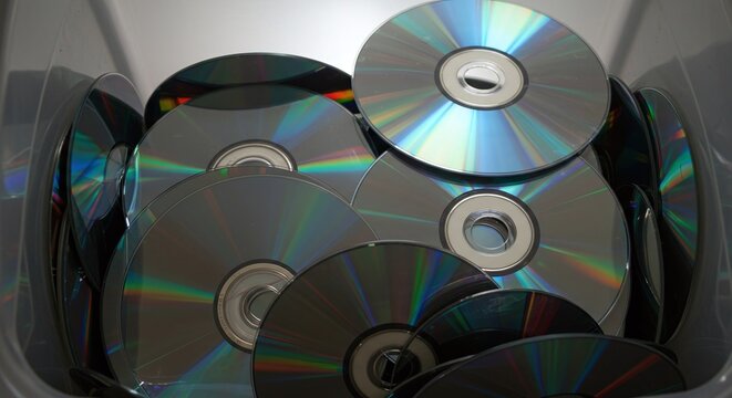 A pile of old CDs and DVDs are collected together as a form of electronic waste for recycling.Concept of recycling obsolete physical media.