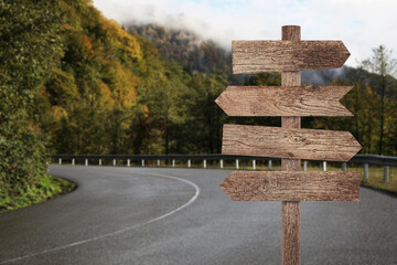 Wooden signpost with arrows pointing in different directions on mountain road