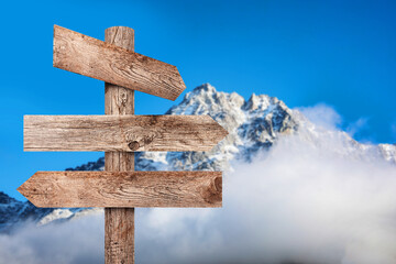 Wooden signpost with arrows pointing in different directions against mountain