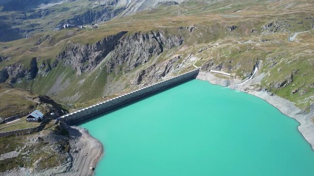 Aerial view of the impressive Diga del Goillet dam holding back a surreal turquoise lake nestled amid rugged mountains, Diga del Goillet, Valle d'Aosta, Italy.