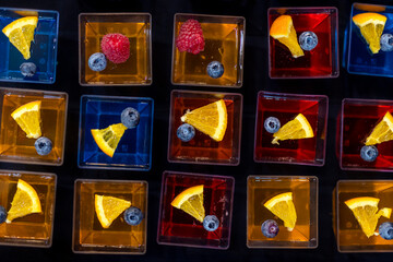 Colorful fruit background with jelly desserts with fresh blueberries raspberries citrus orange on black table