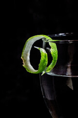 Cocktail glass with lime peel garnish on the rim of the glass