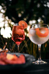 Mixed cocktail drinks and sangria with snacks on restaurant table outdoors at sunset
