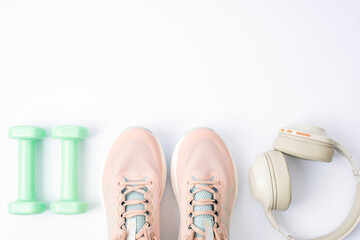 Pink running shoes, dumbbells and wireless earphones on white background. Sports and healthy lifestyle concept. Top view, flat lay, copy space