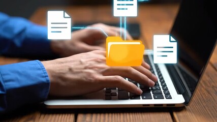Typing on a silver laptop with a digital folder icon displayed above. The laptop sits on a wooden table. The person wears a blue shirt. Data management concept. - Powered by Adobe