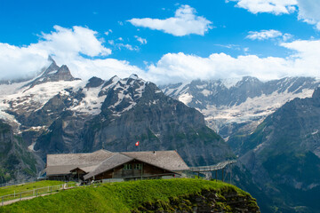 A modern building with angular design set in the Swiss Alps, surrounded by towering snow-covered peaks. Its sleek glass facade contrasts beautifully with the rugged mountain landscape.