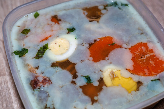 Homemade Aspic Jelly with Meat, Boiled Eggs and Carrots in a Plastic Container, Traditional Slavic Cuisine, Holodets or Studen Dish Close-up