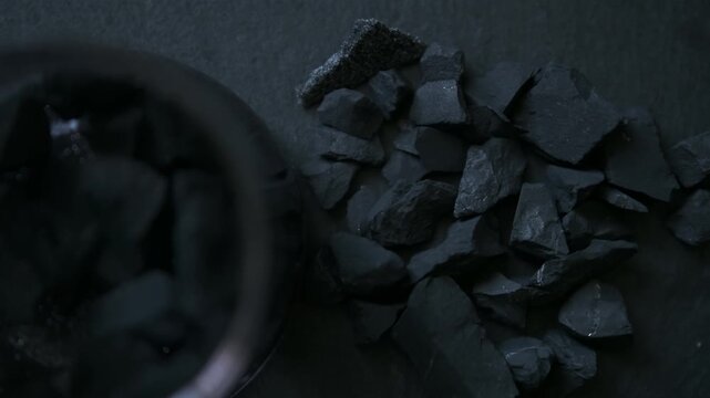 Cinematic still life featuring black shungite stones arranged in water, captured in a calm,  smooth, matte surfaces of the stones. Soft cinematic  texture, form, and natural imperfections