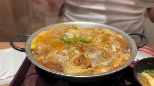 Man eating a traditional hot katsudon with rice and miso soup in a restaurant in Kyoto, Japan