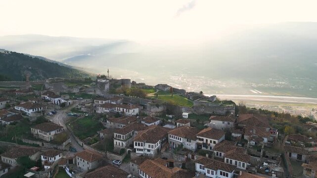 Aerial view of the historic Berat Castle perched high above the city, with its stone walls contrasting against the red-tiled roofs, Berat, Berat County, Albania.
