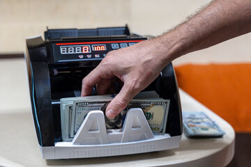 Taking counted cash from digital money counting machine. Hand retrieving a stack of 100 US dollar...