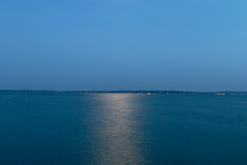 Serene twilight over a vast lake with distant lights reflecting on the water