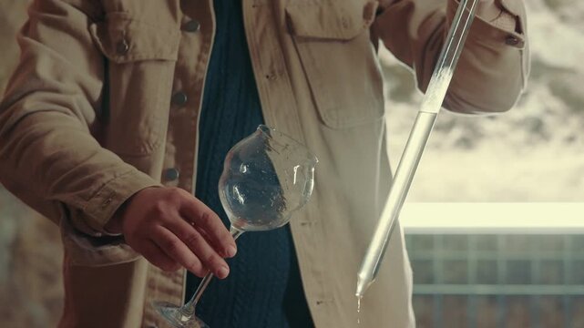 Close up shot winemaker or sommelier is pouring red wine in transparent glass for tasting