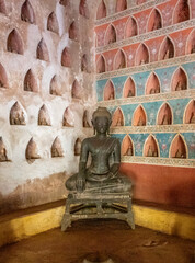 Historical bronze Buddah sculpture surrounded by smaller figures set in wall niches, Wat Si Saket, Vientiane, Laos.