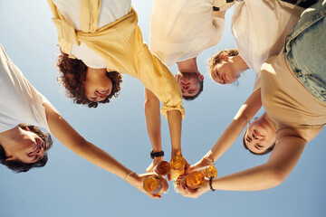 Upside down. View from below of people that are cheering with beer bottles