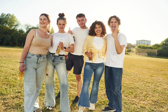 Alcohol in hands, party time. Young friends are having fun on the field