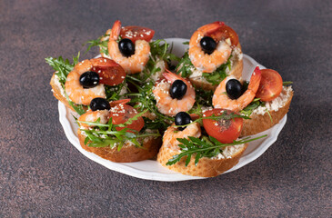 Bruschetta with shrimps, arugula, cream cheese and cherry tomatoes on white plate