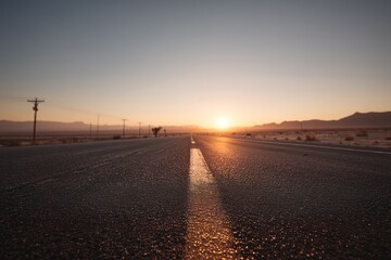 Desert Road at Sunset with Power Lines and Mountains in the Background