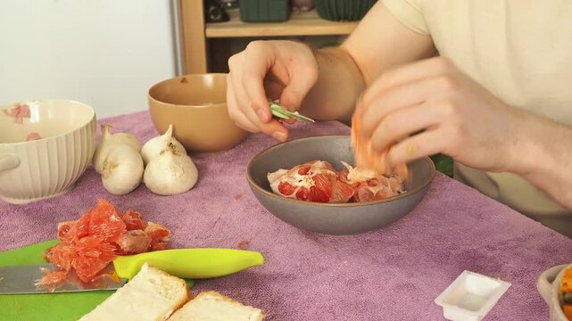 A man peels a ripe grapefruit for breakfast.
