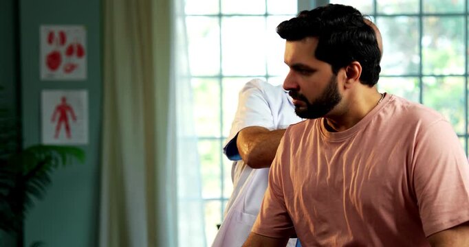 Indian male doctor treating patient during routine health checkup as experienced physician examines young man with stethoscope in modern Indian clinic OPD healthcare consultation visit