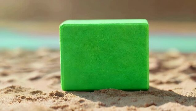 Minimal wellness 4K product video of green yoga block placed on sandy beige background slowly zooming to emphasize fitness balance 