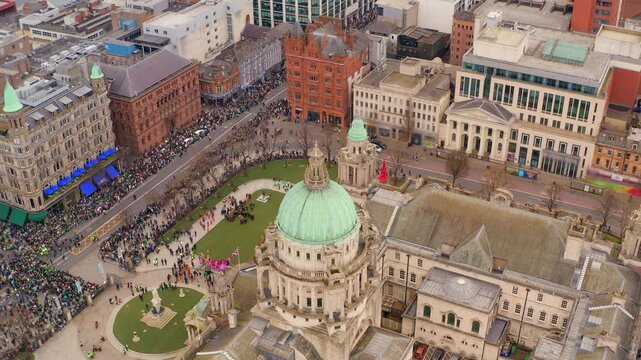 Static aerial view of crowds assembling around Belfast City Hall ahead of St. Patrick&rsquo;s Day celebrations