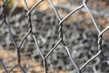 Abstract metal fence pattern with twisted steel mesh wire texture showing security and protection concept in blurred industrial background with calm atmosphere