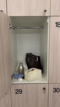 Open gym locker with personal items including sports bag, towel, makeup abg and water bottle.