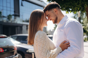 By parking lot with cars. Happy couple together outdoors