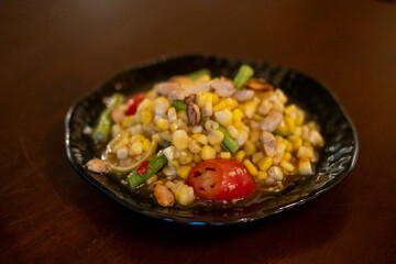 Spicy corn with salted egg salad, or Som Tum with corn, served on plate.