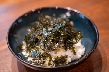 A bowl of rice with seaweed served on the table