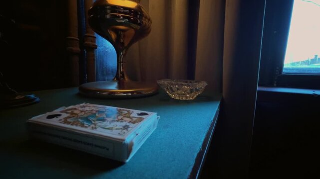 Classic interior. Vintage and antique items on a table with a cloth cover. Table lamp, lighter, cigarette case, pipe, ashtray, playing cards, statuette