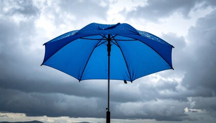 Blue Umbrella Against Cloudy Overcast Sky Symbolizing Shelter, Contrast, and Preparedness in Stormy Weather