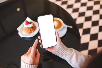 Top view mockup image of a woman holding and using mobile phone with blank desktop screen in cafe