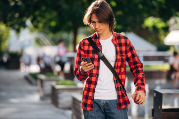 At sunny daytime. Young student is having a walk in the town