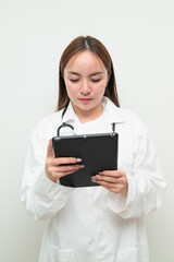 Portrait of young Asian female doctor against white background using tablet computer