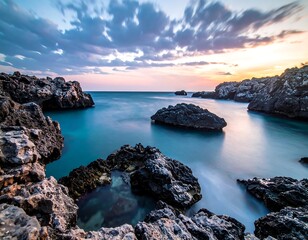 Coastal scene with rocky cliffs, calm water, and a colorful sunset