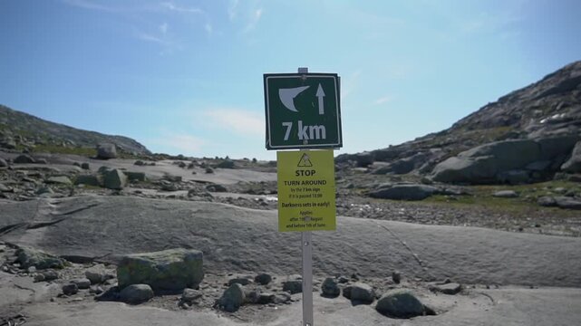 Trail sign on the hiking route to Trolltunga in Vestland, Norway. Mountain path near Skjeggedal above Odda showing remaining distance. Famous pedestrian trail in rugged Scandinavian landscape.