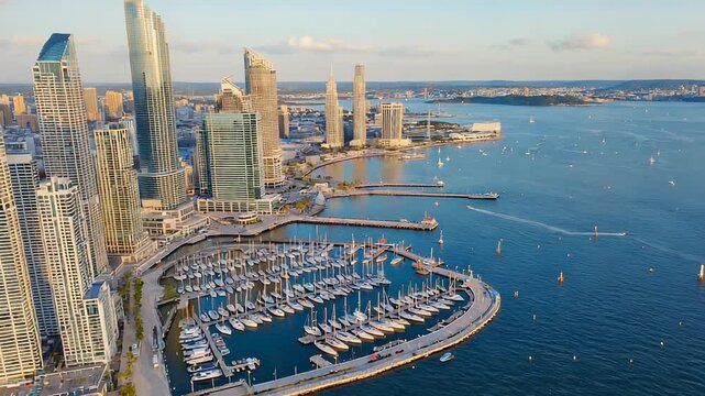 Aerial view of a luxury marina with numerous yachts and sailboats docked, showcasing a vibrant coastal lifestyle and upscale waterfront community.