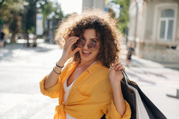 Fototapeta premium In stylish sunglasses, funny. Happy woman is with shopping bags in town