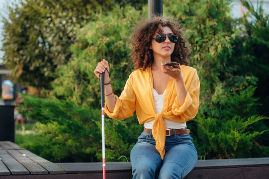 Talking by phone. A blind woman is in the modern city at daytime