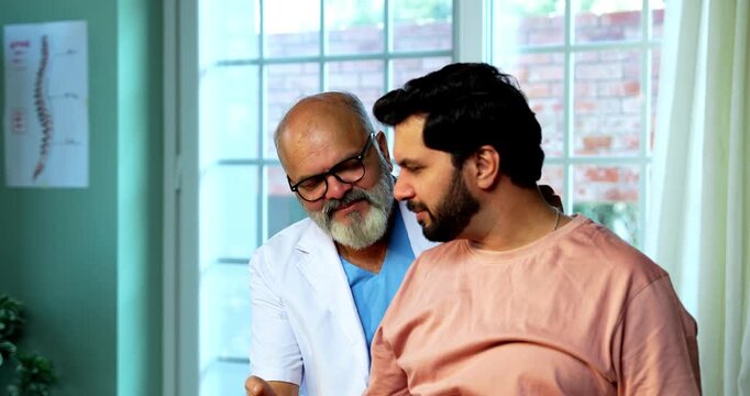 Indian physiotherapist treating young patient for neck and shoulder pain during physical therapy session as experienced male therapist provides manual treatment inside modern Indian clinic