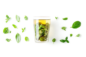 Refreshing herbal tea in a glass with basil leaves around it