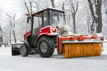 City street cleaning vehicle with rotating brush . Tractor removing snow from sidewalk with brush and steel blade