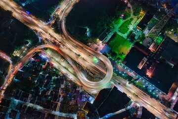 Aerial view of illuminated roads curving through the urban landscape, where streaks of light paint a vibrant contrast against the dark cityscape, Dhaka, Dhaka Division, Bangladesh.