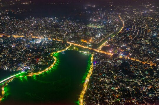 Aerial view of the vibrant Hatirjheel lake reflecting city lights, split by illuminated bridges and surrounded by dense urban sprawl, Dhaka, Dhaka Division, Bangladesh.