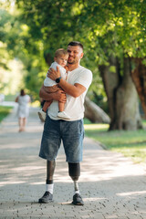 Obraz premium Conception of love and care, standing. Father that is amputee with prosthesis is with his little son in the park