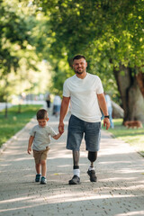 Obraz premium Father that is amputee with prosthesis is with his little son in the park