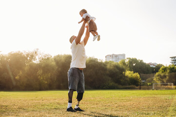 Fototapeta premium Feeling good, holding kid in hands. The amputee father is with his son on the field